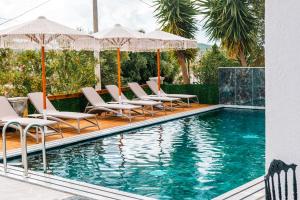a swimming pool with lounge chairs and umbrellas at Vila Malo in Ksamil