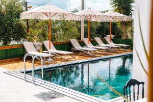 a row of chairs and umbrellas next to a swimming pool at Vila Malo in Ksamil