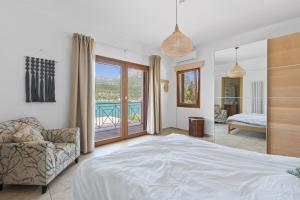 a bedroom with a bed and a chair and a balcony at Villa Helia in Yénion +15 photos