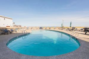 a swimming pool with tables and chairs in front of a beach at Sea View Inn in Old Orchard Beach