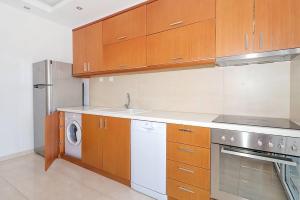 a kitchen with wooden cabinets and a washer and dryer at Kai Guest House in Polychrono +5 photos