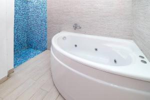 a white bath tub in a bathroom with a shower at Kai Guest House in Polychrono