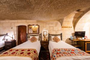 a bedroom with two beds and a tv at Tulip Cave Suites in Göreme +185 photos
