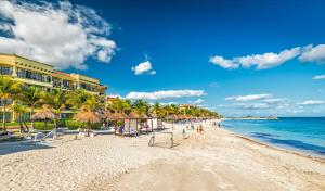 una playa con sombrillas y el océano en un día soleado en Hotel Marina El Cid Spa & Beach Resort - All Inclusive, en Puerto Morelos