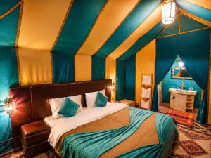 a room with a bed with blue and yellow walls at Luxury Sahara Desert Glamping Experience in Merzouga in Merzouga +23 photos