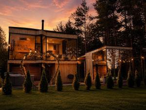 a house in a yard with a sunset in the background at Luxury Tahkuranna SPA villa Pärnu in Laadi