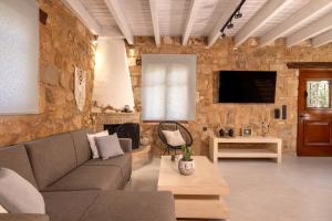 a living room with a couch and a tv at Artemis Luxury Villa in Méson Yerakaríon