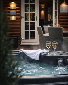 two glasses of wine sitting on a table in a hot tub at Grand Fir Lodge - The Hollies Retreats in Tarporley