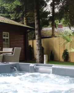 a hot tub in a yard next to a house at Grand Fir Lodge - The Hollies Retreats in Tarporley +8 photos