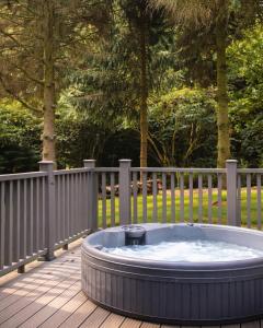 a hot tub on a deck next to a fence at Noble Fir Lodge - The Hollies Retreats in Oakmere +4 photos