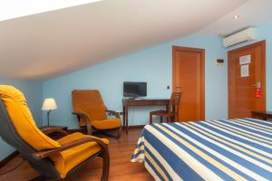 a bedroom with a bed and chairs and a desk at Hotel Bufon de Arenillas in Vidiago