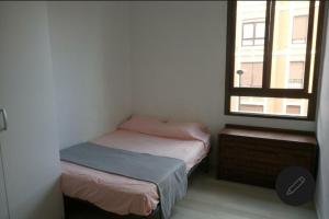 a small bedroom with two beds and a window at Bilbao Habitaciones in Bilbao