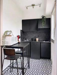 a kitchen with black cabinets and a table and chairs at Splendide studio de Giverny Vernon Paris in Vernon