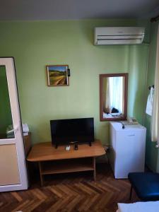 a room with a desk with a television and a refrigerator at Водстрой in Popovo