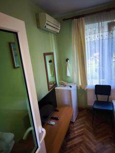 a room with a desk with a television and a window at Водстрой in Popovo
