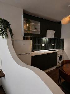 a kitchen with a white refrigerator and black cabinets at Studio chic et confortable in Lorgues