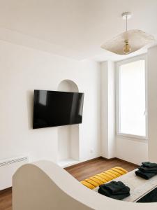 a white living room with a tv on the wall at Studio chic et confortable in Lorgues