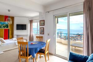 a living room with a dining room table and a balcony at León Hotel Saranda in Sarandë