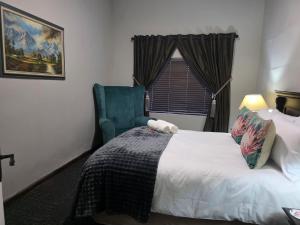 a bedroom with a bed and a chair and a window at 5Res Stay in Queenstown