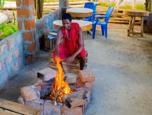 a man is sitting over a fire pit at Breezy Lodge in Moshi
