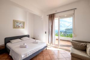 a bedroom with a bed and a large window at León Hotel Saranda in Sarandë