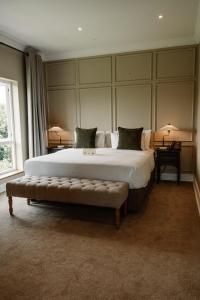 a large bedroom with a large bed with a bench at Redlands Hotel in Pietermaritzburg