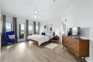 a bedroom with a bed and a tv and a blue chair at Pets Stay Free, Breezy, Stylish Island Elegance in Lago Vista