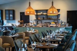 a restaurant with wooden tables and chairs and lights at Hotel Grimsborgir by Keahotels in Ásborgir