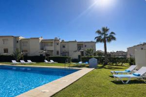 a swimming pool with lounge chairs and a resort at Nuevo Torrox Deluxe Beach & Piscina in Torrox