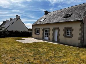 an old stone house with a grass yard in front of it at Maison de plage in Guissény