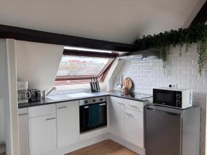 a kitchen with white cabinets and a black microwave at Le face mer in Le Portel