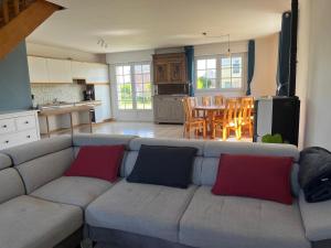 a living room with a gray couch with red and blue pillows at Maison de plage in Guissény