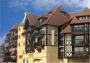 um grande edifício de apartamentos com telhado castanho em Mercure Deauville Centre em Deauville