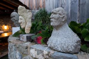 zwei Statuen von Menschen, die auf einer Steinmauer sitzen in der Unterkunft Corte della Maddalena in Busana