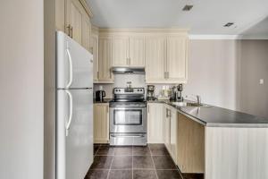 a kitchen with white cabinets and a stainless steel refrigerator at INITIAL - CAVALIER - Chutes-Montmorency in Boischâtel