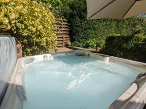 a jacuzzi tub in a garden with bushes at The Lawns House in Holt