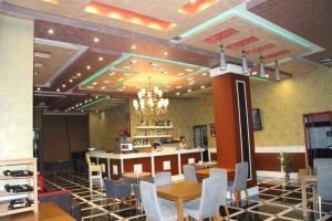 a restaurant with a bar and tables and chairs at Hotel KTHELLA in Rrëshen