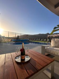 a bottle of champagne and two wine glasses on a wooden table at Villa Coco in Mogán