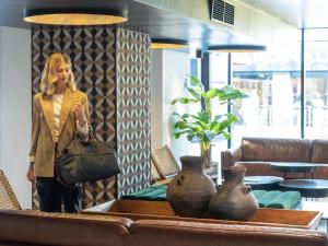 a woman is standing next to a table with vases at Almacruz Hotel y Centro de Convenciones (Ex Galerías) in Santiago