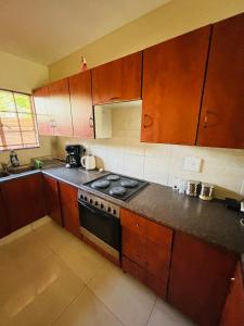 a kitchen with wooden cabinets and a stove top oven at Sleep in Crestwave villas in eMalahleni