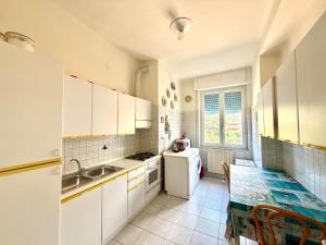 eine Küche mit weißen Schränken, einer Spüle und einem Tisch in der Unterkunft Appartamento Roggero in Levanto