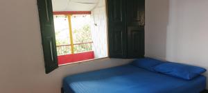 a blue bed in a room with a window at Finca la pilarica in Istmina