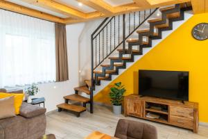 a living room with a television and a staircase at Apartmaji MM in Bohinj