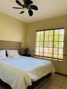 a bedroom with a bed and a ceiling fan at Sleep in Crestwave villas in eMalahleni