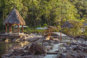 a resort with a river and rocks and umbrellas at Gaia Riverlodge in San Ignacio