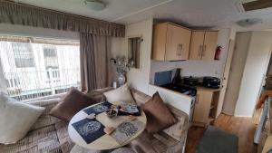 a living room with a table and a couch at Golden sands 326 3 bedroomed caravan in Ingoldmells +25 photos