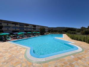 a swimming pool in a resort with chairs and umbrellas at Residenza Verde Blu - ArgonautiVacanze in Capoliveri