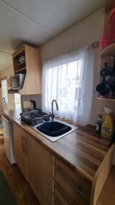 a kitchen counter with a sink and a window at Golden sands 326 3 bedroomed caravan in Ingoldmells
