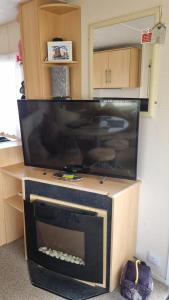 a large flat screen tv sitting on top of a cabinet at Golden sands 326 3 bedroomed caravan in Ingoldmells