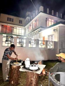 a man cooking food on a grill on a table at vishwaram Homestay in Chail
